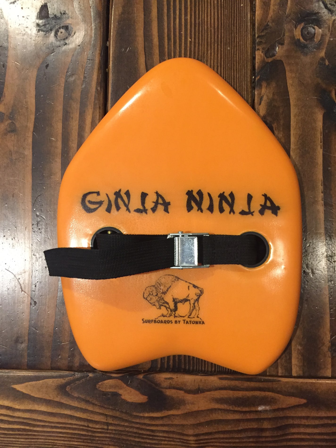 Orange Ginja Ninja handplane with a black hand strap and Tatonka logo